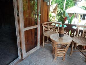 einen Tisch und Stühle auf einer Veranda mit einer Vase darauf in der Unterkunft Wooden House and Spa Ubud in Ubud