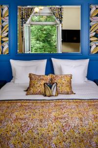 a blue bedroom with a bed with pillows and a window at Hotel The Rose by Goeres in Luxembourg