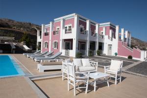 un edificio rosa y blanco con sillas y piscina en Rose Suites en Vourvoúlos