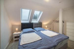 een slaapkamer met een bed met blauwe lakens en 2 ramen bij Ferienwohnung 2 in Bad Lauterberg