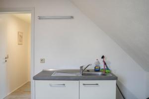 een witte keuken met een wastafel en een trap bij Ferienwohnung 2 in Bad Lauterberg