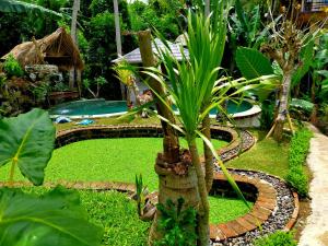 einen Garten mit einer Palme und einem Pool in der Unterkunft Wooden House and Spa Ubud in Ubud