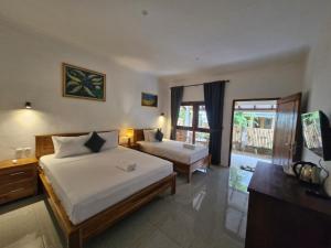 a hotel room with two beds and a television at Bale Kebon Rangsot in Pawenang