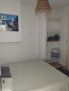 a bedroom with a white bed and shelves at Appartement 2 à Carthage byrsa in Douar ech Chott