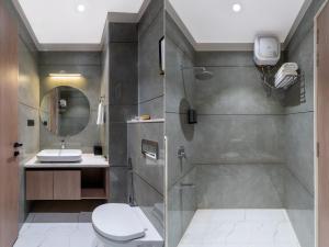 a bathroom with a shower and a toilet and a sink at Hotel Blue Chip By Downtown - Near Udaipur Airport in Dabok