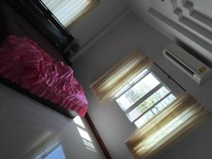 1 dormitorio con 2 ventanas y 1 cama con almohada en Wan Ton vacation home, en Nakhon Sawan