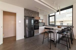 eine Küche mit einem schwarzen Kühlschrank und schwarzen Hockern in der Unterkunft Amazing Penthouse on Gordon Beach 8 guests in Tel Aviv