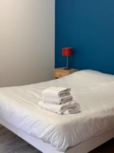 - une pile de serviettes assises sur un lit dans l'établissement KOSY Appart'Hôtel 7ème Art, à Saint-Avold