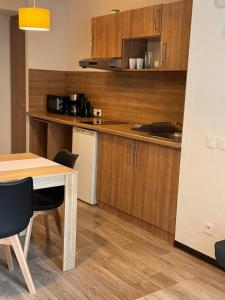 - une cuisine avec des placards en bois, une table et des chaises dans l'établissement KOSY Appart'Hôtel 7ème Art, à Saint-Avold