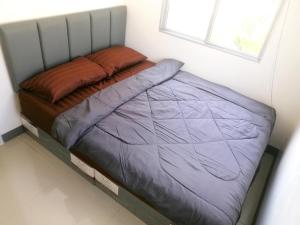 uma pequena cama num quarto com uma janela em NIDO Guest House em Ban Bang Phang