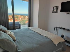 a bedroom with a bed and a large window at La sentinelle du cap Bear in Port-Vendres