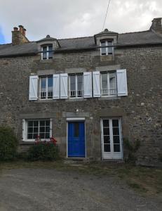 una casa de ladrillo con una puerta y ventanas azules en Kerfly, en Plouër-sur-Rance