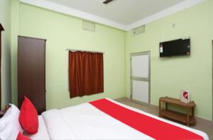 1 dormitorio con 1 cama grande y TV en la pared en Goroomgo Somnath Puri, en Puri