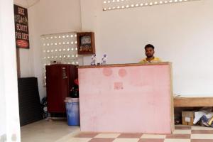 un hombre parado detrás de una puerta rosa en una habitación en Goroomgo Somnath Puri, en Puri
