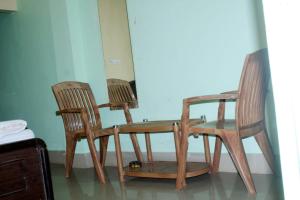 2 sillas de madera y mesa con ordenador portátil en Goroomgo Somnath Puri, en Puri