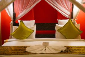 1 cama con almohadas amarillas y pared roja en Jafferji House en Zanzíbar