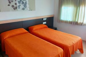 2 Betten in einem Zimmer mit orangefarbener Bettwäsche in der Unterkunft Luz Marina in Torredembarra
