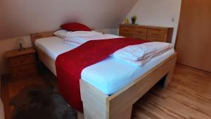 a bedroom with a bed with white sheets and red blanket at Ferienwohnung Sommerfeld in Bispingen