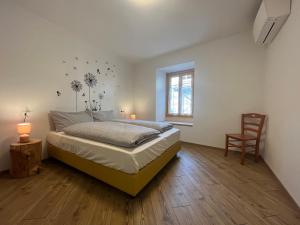 1 dormitorio con 1 cama, 1 silla y 1 ventana en Borgo Bliss Apartment, en Tenno