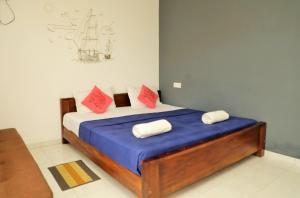 a bedroom with a bed with blue sheets and red pillows at Andorra Tourist Resort Anuradhapura in Anuradhapura