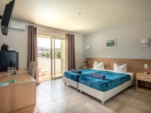 アルガジョラにあるFerienhotel Maristellaのベッドとテレビが備わるホテルルームです。