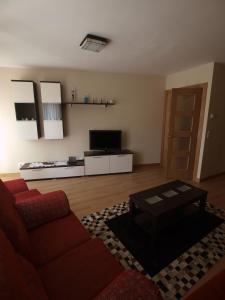 a living room with a red couch and a table at Casa Rural El Cipres in Santo Domingo de Silos