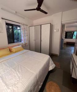 a bedroom with a white bed and a ceiling fan at Home Stay in Mumbai