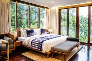 Un dormitorio con una cama grande y grandes ventanales. en Villa Leceni Canggu by Nakula, en Canggu