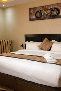 盧薩卡的住宿－Milestone Hotels，一张位于酒店房间的床,墙上挂着摩托车