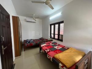 1 dormitorio con 2 camas y ventana en Happy Villa Homestay - 2, en Chelakara