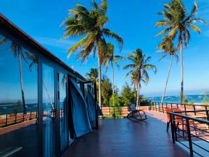 een balkon van een resort met palmbomen en de oceaan bij Homestay Phú Yên - Tuy Hòa - Long Thủy Song Ngư House in Tuy Hoa