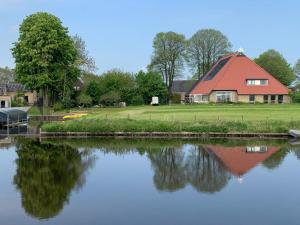a house with a red roof next to a river at De Middelste Dam in Mildam