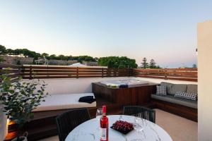 balkon z wanną z hydromasażem i stołem z butelką wina w obiekcie Le Bijou Luxury Suites Rethymno w Retimnie