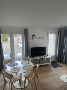 un salon avec une table et une télévision dans l'établissement Maisonnette La petite Jeanne, à Boves