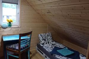 a room with a bed and a chair in a log cabin at Uroczy domek na Mazurach in Nowe Kiejkuty