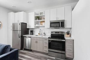 a kitchen with white cabinets and stainless steel appliances at Mid-Century Modern Studio CozySuites Downtown in Indianapolis