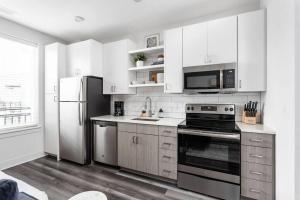 a kitchen with white cabinets and a stove and refrigerator at Dream Apartment near Whole Foods CozySuites in Indianapolis