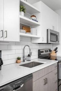 a white kitchen with a sink and a microwave at Dream Apartment near Whole Foods CozySuites in Indianapolis