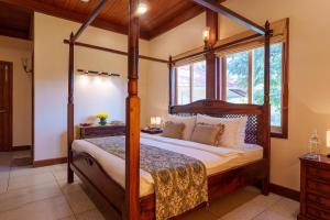 a bedroom with a four poster canopy bed with a window at amã Stays & Trails Skyfall , Kashid in Kashid +44 photos