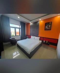 - une chambre avec un lit et un mur orange dans l'établissement Hưng Phú Hotel HCM, à Hô-Chi-Minh-Ville