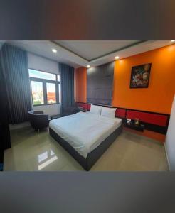ein Schlafzimmer mit einem Bett und einer orangefarbenen Wand in der Unterkunft Hưng Phú Hotel HCM in Ho-Chi-Minh-Stadt + 15 Fotos