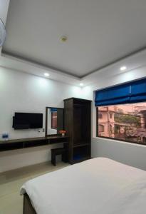 ein Schlafzimmer mit einem Bett, einem Fernseher und einem Fenster in der Unterkunft Hưng Phú Hotel HCM in Ho-Chi-Minh-Stadt