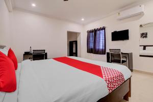 a bedroom with a red and white bed and a tv at Super OYO Flagship 81926 Hotel MN Stays in Vijayawāda