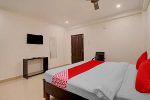 a bedroom with a red and white bed and a television at Super OYO Flagship 81926 Hotel MN Stays in Vijayawāda