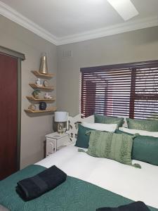 a bedroom with a bed with green and white pillows at Urban Oasis Cape Town in Cape Town