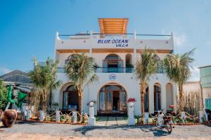 a building with palm trees in front of it at BLUE OCEAN VILLA in Cu Lao Thu
