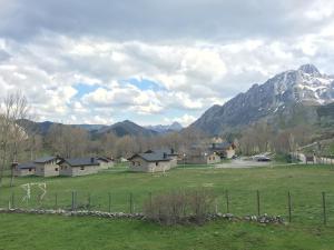 a group of houses in a field with a mountain at Casa de Montaña Alto Curueño in Lugueros