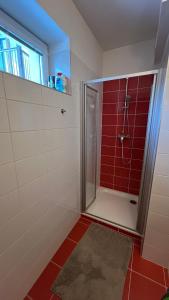 uma casa de banho com um chuveiro com azulejos vermelhos em Apartmán Razula em Vsetín