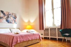 a bedroom with a bed with a red blanket and a window at Casa Del Teatro in Pavia