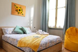 a bedroom with a bed with a yellow blanket and a window at Casa Del Teatro in Pavia